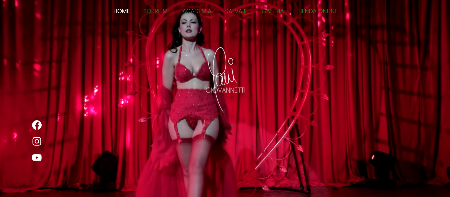 Mujer en lencería roja posando frente a un arco en forma de corazón y cortinas rojas en una página web.